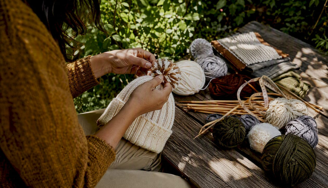 Close-up of hands attaching pom pom to beanie